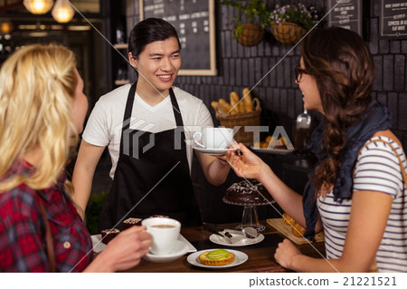 Smiling waiter serving a coffee to a customer Smiling waiter serving a coffee to a customer 21221521