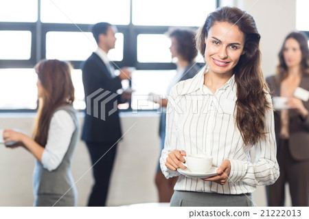 Businesswoman smiling at camera while her colleagues standing in 21222013
