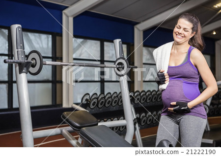 Smiling pregnant woman standing next to bench 21222190