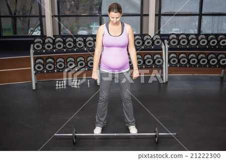 Determined woman looking at barbell Determined woman looking at barbell 21222300