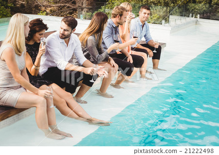 Young people sitting by swimming pool Young people sitting by swimming pool 21222498