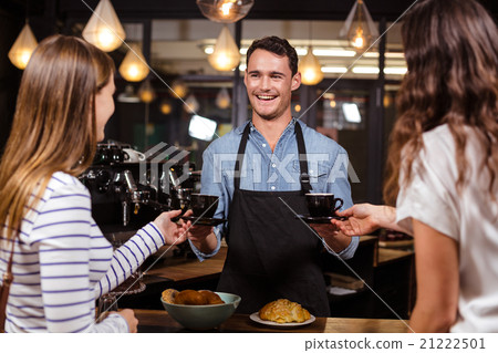 Smiling barista giving coffees to women 21222501