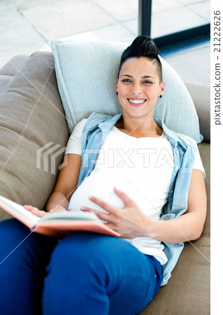 Portrait of pregnant woman reading a book while lying on sofa 21222626