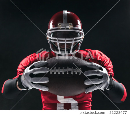 American football player posing with ball on black 21228477
