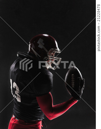 American football player posing with ball on black American football player posing with ball on black 21228478