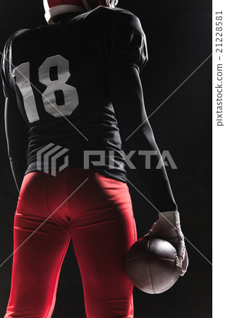 American football player posing with ball on black 21228581