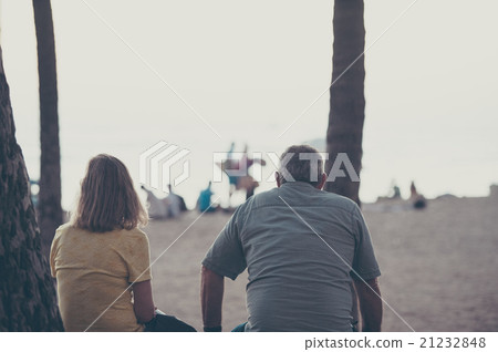 A middle-aged couple sitting on a sandy beach 21232848