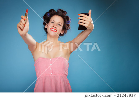 Girl in hair curlers applying red lipstick 21245937