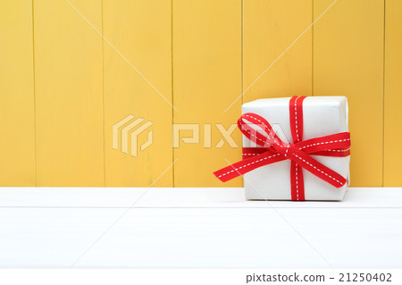 Cute white and red gift box on yellow background 21250402