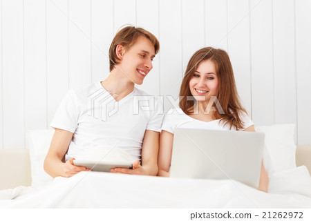 happy couple with laptop on internet in bed 21262972