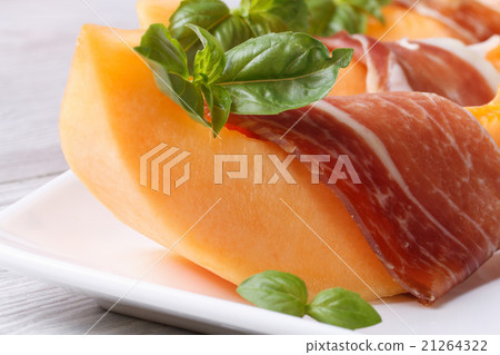slice of melon wrapped in prosciutto on a plate slice of melon wrapped in prosciutto on a plate 21264322