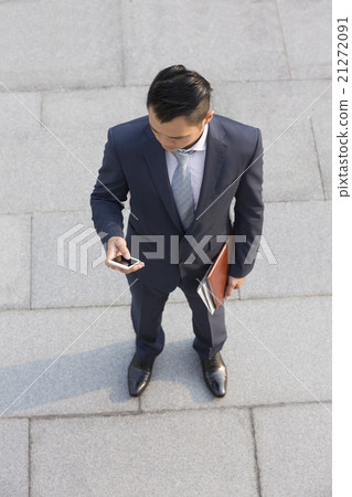 Asian businessman using his smart phone. Asian businessman using his smart phone. 21272091