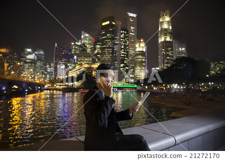 Chinese businessman outdoors at night talking on the phone. 21272170