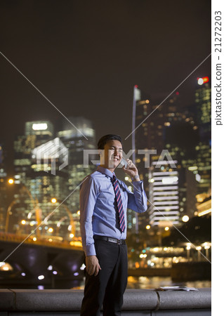Chinese businessman outdoors at night talking on the phone. 21272203