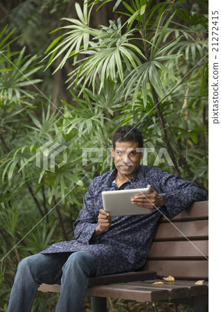 Indian man wearing a kurta and using tablet computer. Indian man wearing a kurta and using tablet computer. 21272415