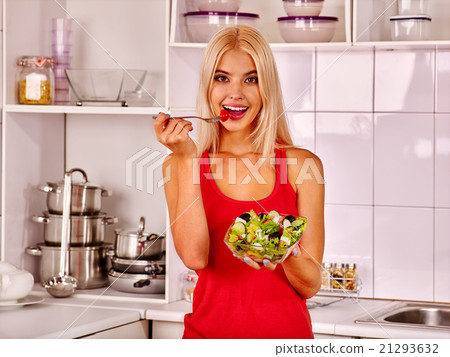 Woman eating salad at kitchen. Woman eating salad at kitchen. 21293632