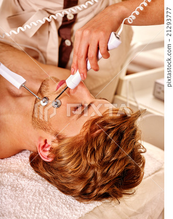 Young man receiving electric facial massage. Young man receiving electric facial massage. 21293777