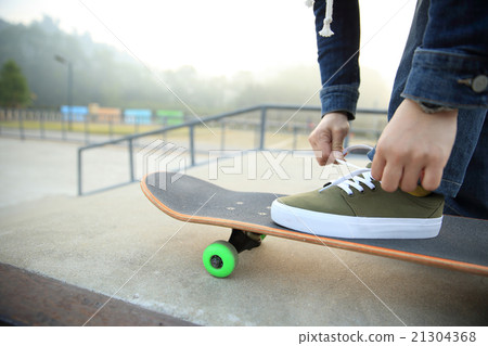 skateboarder tying shoelace at skatepark skateboarder tying shoelace at skatepark 21304368