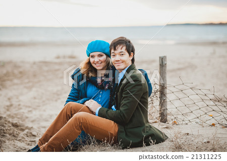 young couple sitting and posing on the beach in young couple sitting and posing on the beach in 21311225