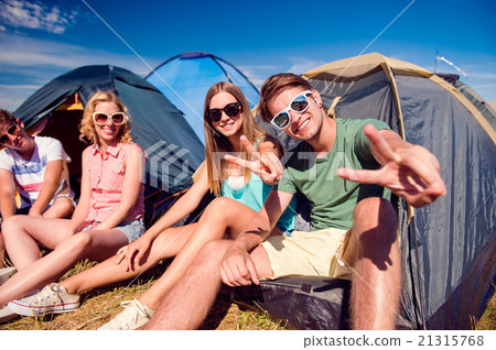 Teenagers sitting on the ground in front of tents Teenagers sitting on the ground in front of tents 21315768