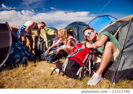 Teenagers sitting on the ground in front of tents 21315790