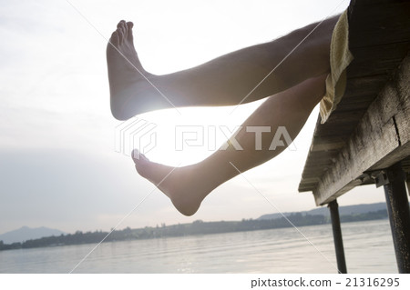 Man on a dock holding his feet in the air Man on a dock holding his feet in the air 21316295