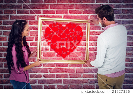 Composite image of smiling couple holding picture frame Composite image of smiling couple holding picture frame 21327336