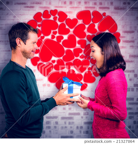 Composite image of excited girlfriend taking gift from boyfriend Composite image of excited girlfriend taking gift from boyfriend 21327864