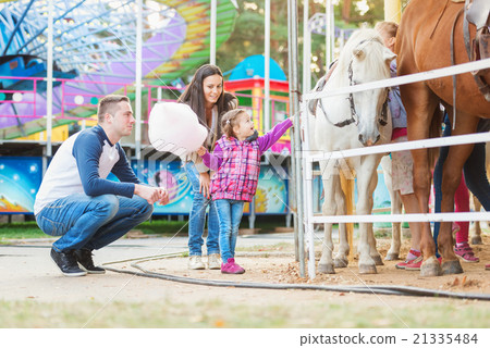 Family with daughter stroking pony in amusement 21335484