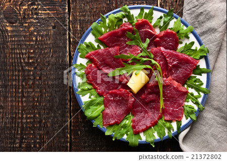 Carpaccio on the white plate on the wooden table 21372802