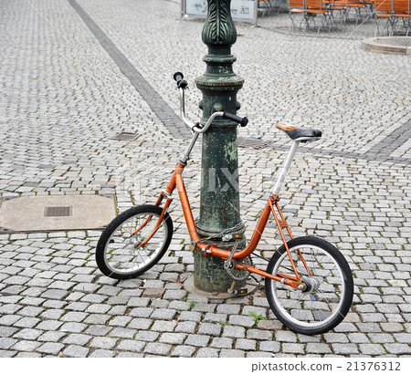 orange bike chained to a pole orange bike chained to a pole 21376312
