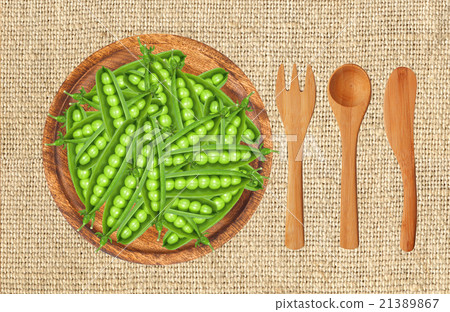 peas on wooden plate with fork, spoon and knife 21389867