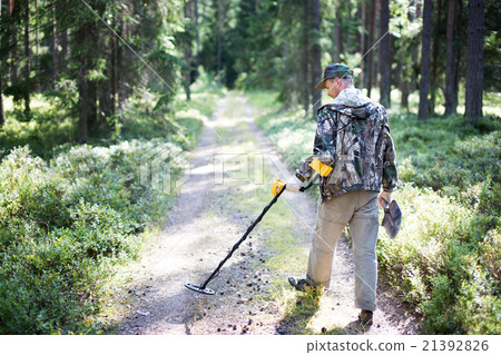 Treasure hunter with metal detector 21392826