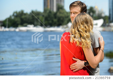 young couple sitting on the sand smiling, hugging young couple sitting on the sand smiling, hugging 21393759