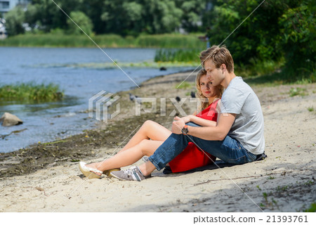 young couple sitting on the sand smiling, hugging young couple sitting on the sand smiling, hugging 21393761