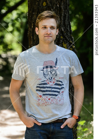 ayoung man wearing T-shirt posing in park ayoung man wearing T-shirt posing in park 21393943