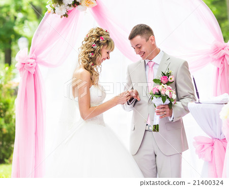Bride putting a ring on groom's finger during 21400324