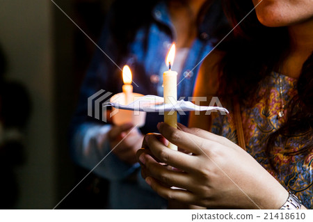 Closeup of people holding candle vigil in darkness 21418610