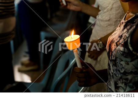 Closeup of people holding candle vigil in darkness 21418611