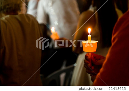 Closeup of people holding candle vigil in darkness 21418613