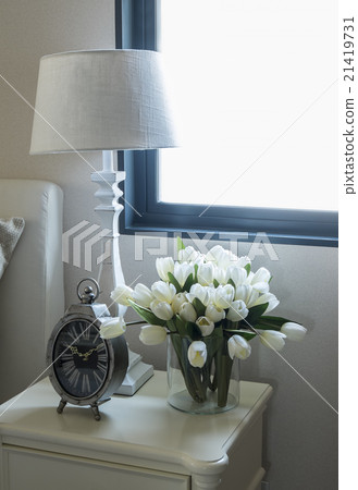white lamp and alarm clock on bedside table 21419731