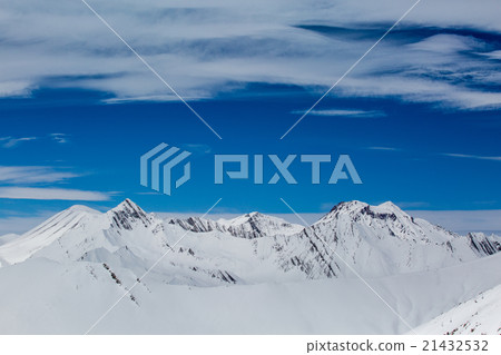 blue skies with clouds over the mountains in snow 21432532