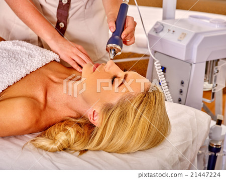 Young woman receiving electric facial massage. 21447224