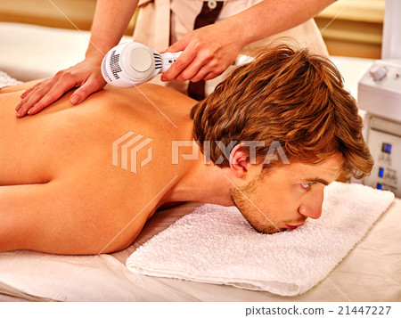 Young man receiving electric facial massage. 21447227