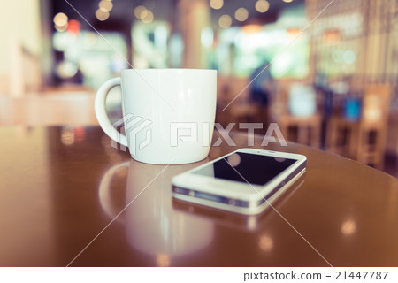 white coffee cup in coffee shop with mobile phone 21447787
