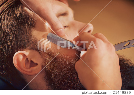 Professional barber shaving beard of his client 21449889