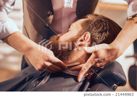 Professional barber shaving beard of his client Professional barber shaving beard of his client 21449963