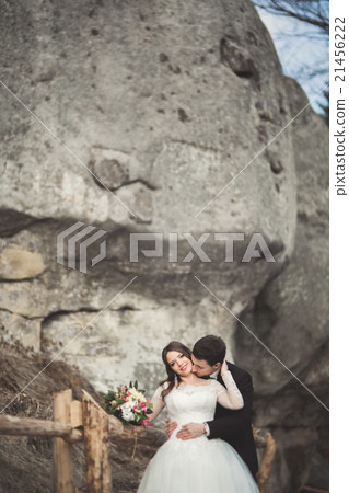 Happy wedding couple kissing and hugging near a Happy wedding couple kissing and hugging near a 21456222