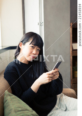A woman using a smartphone on a sofa 21458934