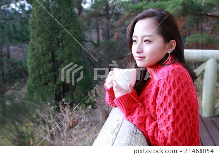 A warm drink and a girl indulging in thought in the winter forest 21468054